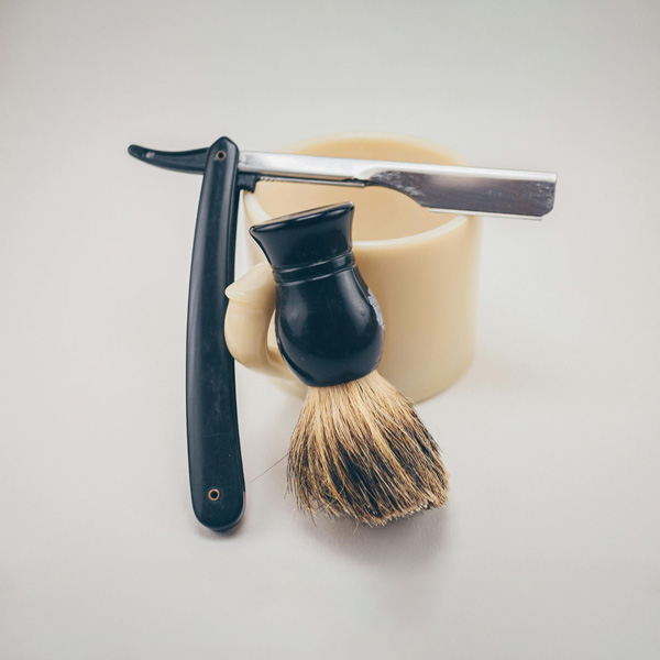 Pinsel und Klinge an Tasse angelehnt